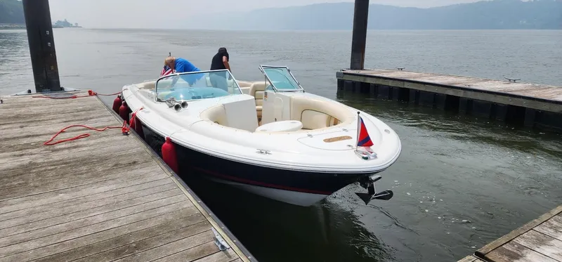 Slide: The Image of 2005 Chris-Craft Launch 28 docked on a calm lake with two people onboard. - 2