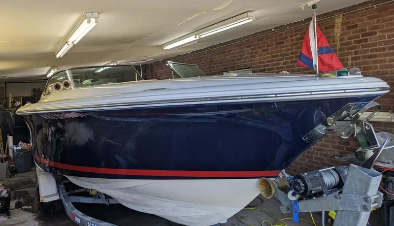 Slide: The Image of 2005 Chris-Craft Launch 28 boat in garage, blue hull, red stripe, nautical flag displayed. - 4