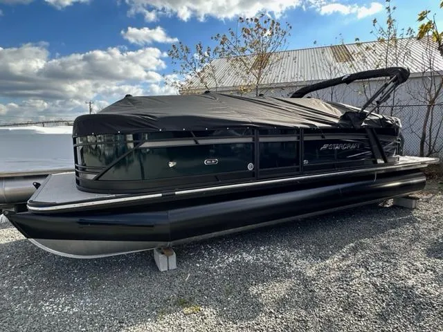 Slide: The Image of 2024 Starcraft SLS-3 pontoon boat with cover, parked on gravel lot. - 7