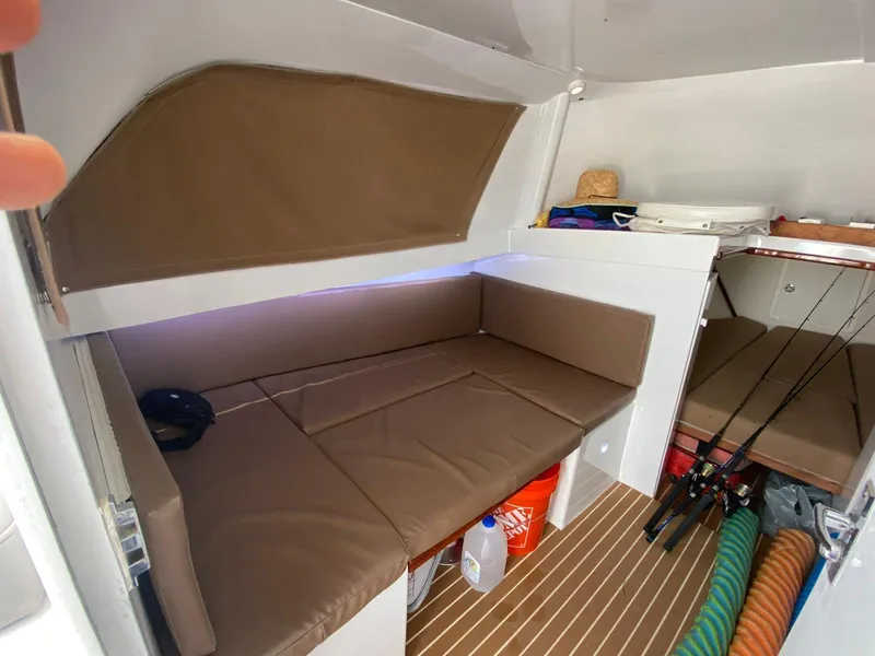 Slide: The Image of 1973 Bertram 31 cabin interior with brown seating, fishing rods, and storage space. - 3