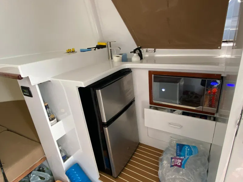 Slide: The Image of 1973 Bertram 31 boat interior with kitchenette, featuring a fridge, microwave, and storage shelves. - 5