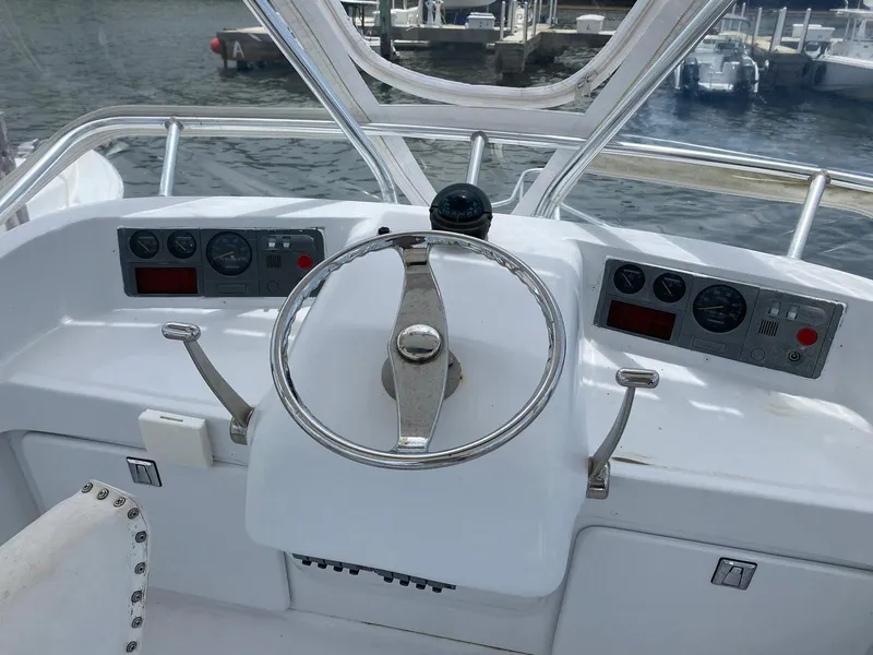 Slide: The Image of 1973 Bertram 31 boat helm with steering wheel and instrument panels, dockside view. - 9