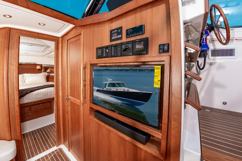 Slide: The Image of 2025 Back Cove 39O yacht interior with wood paneling, TV, and cozy bedroom. - 23