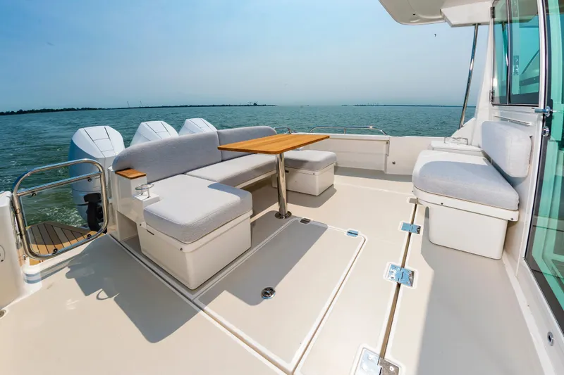 Slide: The Image of 2025 Back Cove 39O boat deck with seating and table, overlooking calm waters. - 9