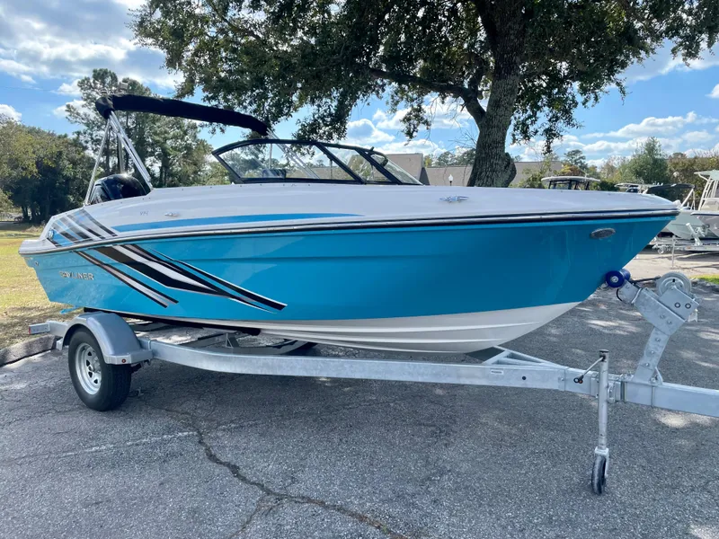 Slide: The Image of 2024 Bayliner VR4 boat on a trailer, blue and white exterior, parked outdoors. - 1