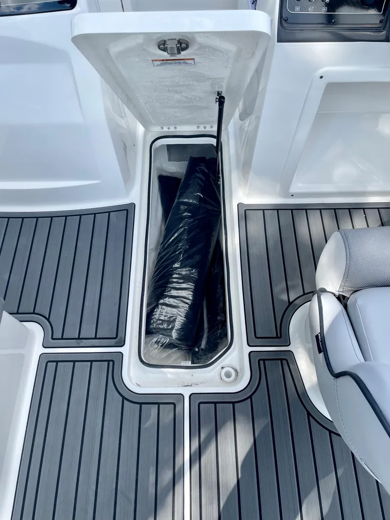 Slide: The Image of 2024 Bayliner VR4 boat storage compartment with black bag on gray deck. - 11