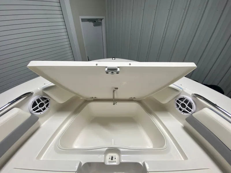 Slide: The Image of 2024 Robalo R207 Dual Console boat storage compartment with open lid and built-in speakers. - 20
