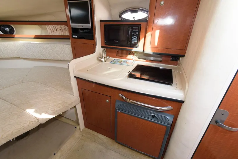 Slide: The Image of 2005 Sea Ray 280 Sundancer interior kitchen with microwave, stove, and sink. - 7
