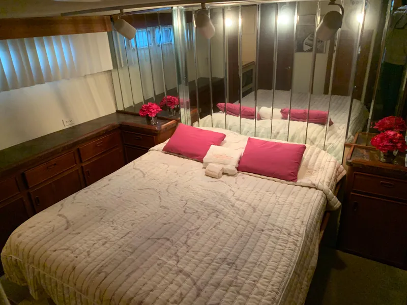 Slide: The Image of 1982 Trojan F 40 yacht bedroom with mirrored wall, pink pillows, and wooden cabinets. - 38