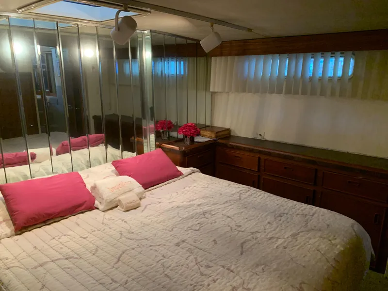 Slide: The Image of 1982 Trojan F 40 yacht bedroom with mirrored wall, pink pillows, and cozy lighting. - 40