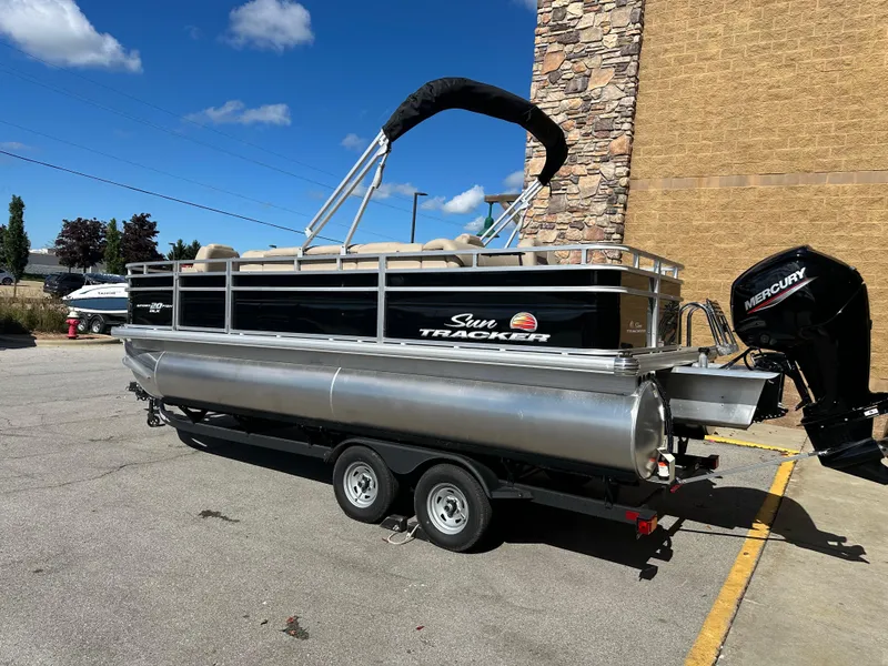 Slide: The Image of 2024 Sun Tracker SportFish 20 DLX pontoon boat on trailer, parked outdoors. - 2
