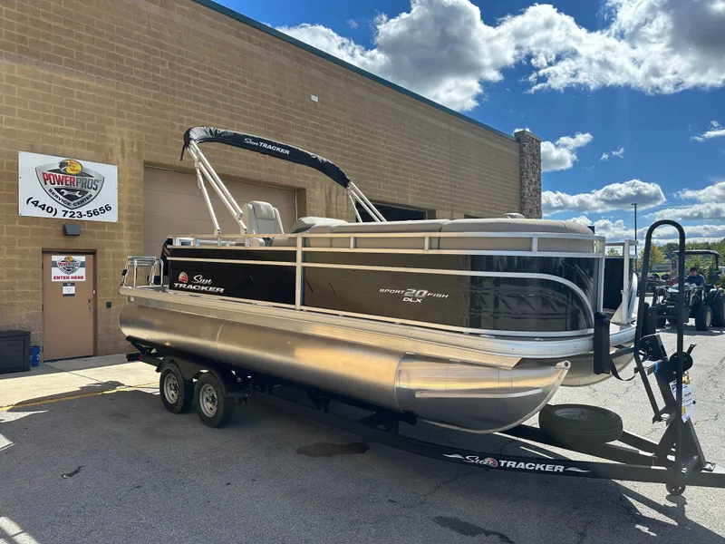 Slide: The Image of 2024 Sun Tracker SportFish 20 DLX pontoon boat on trailer, parked outside dealership. - 4