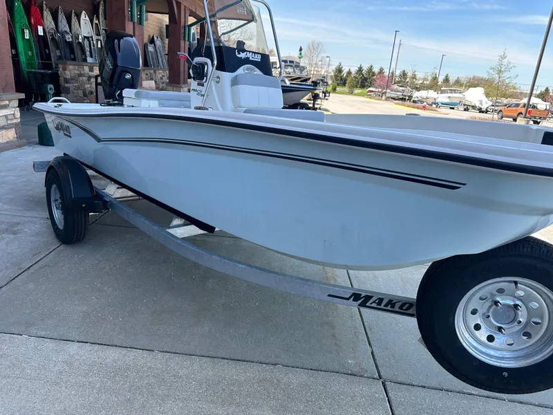 Slide: The Image of 2024 Mako Pro Skiff 15 CC boat on a trailer, displayed outdoors. - 2