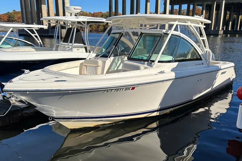 Slide: The Image of 2012 Pursuit DC 265 Dual Console boat docked on calm water. - 10