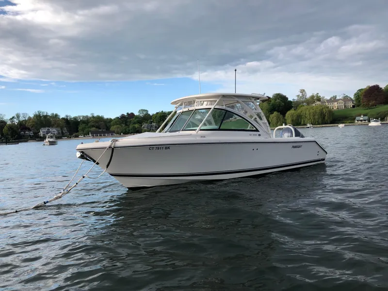 Slide: The Image of 2012 Pursuit DC 265 Dual Console boat anchored on a calm lake. - 2
