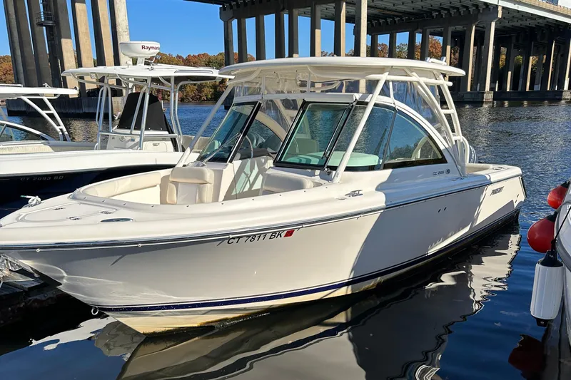 Slide: The Image of 2012 Pursuit DC 265 Dual Console boat docked near a bridge. - 6