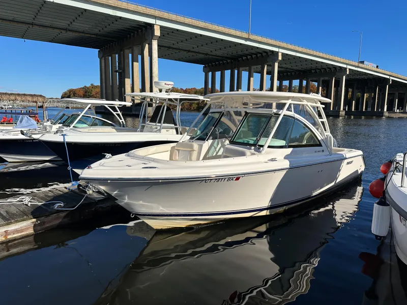 Slide: The Image of 2012 Pursuit DC 265 Dual Console boat docked near a bridge on a sunny day. - 9