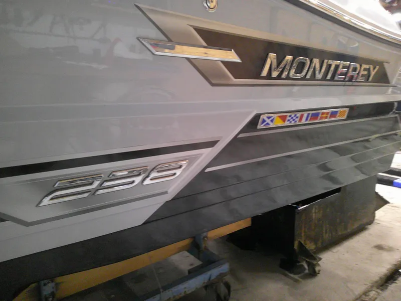 Slide: The Image of 2023 Monterey 238 Super Sport boat side view with logo and nautical flags. - 3