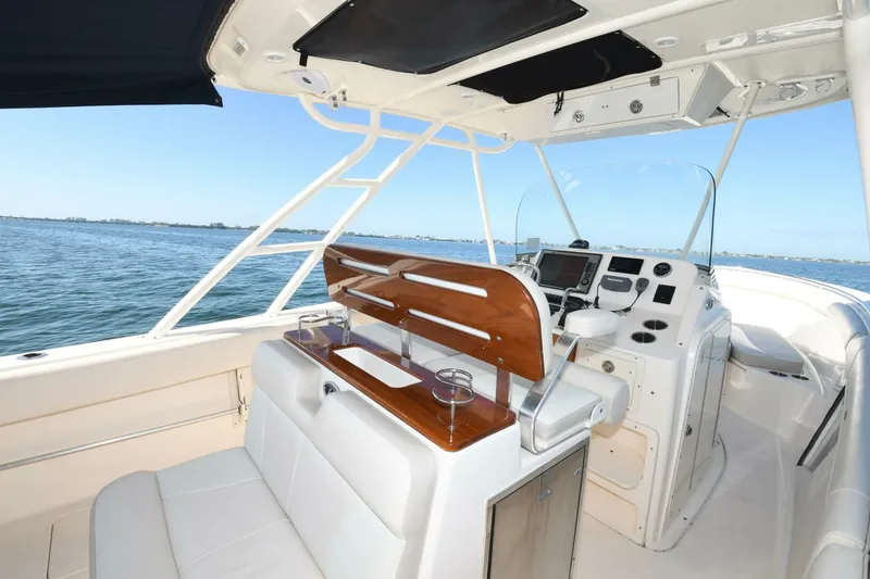 Slide: The Image of 2011 Pursuit S310 boat interior with helm station and seating, on calm water. - 14