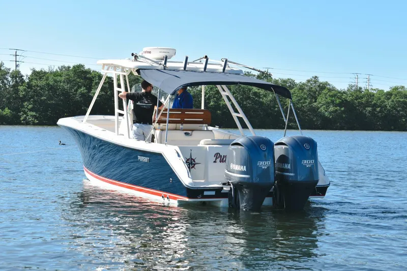 Slide: The Image of 2011 Pursuit S310 boat with twin Yamaha engines on a calm lake. - 22