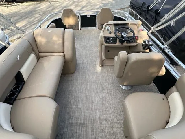 Slide: The Image of 2024 Starcraft LX 18 F pontoon boat interior with beige seating and steering console. - 2