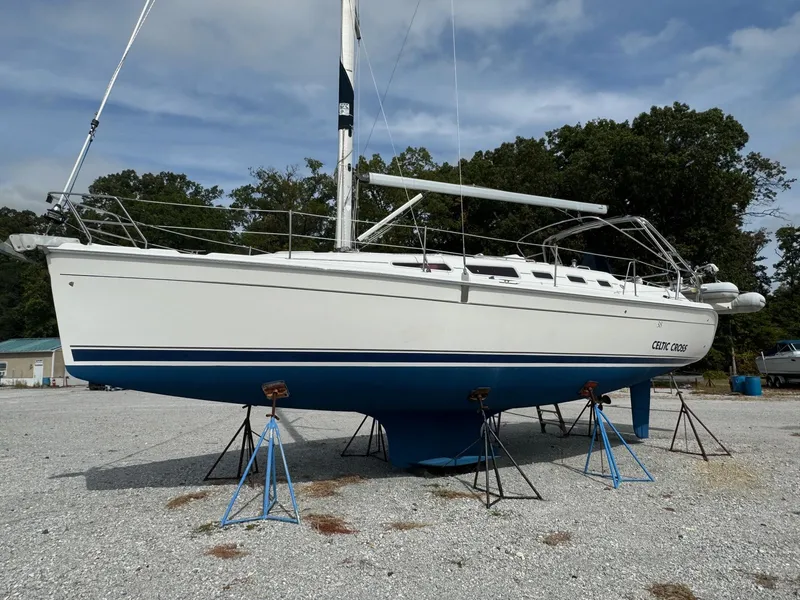 The Image of 2008 Hunter 38 sailboat on stands, white hull with blue stripe, outdoor setting. - 0