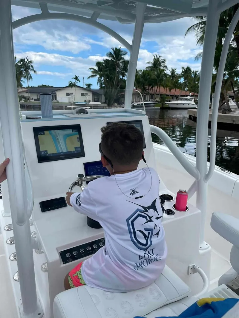 Slide: The Image of Child steering a 2023 CG Boat Works 35 M-Series boat on a sunny day. - 34