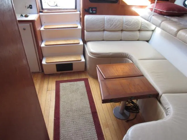 Slide: The Image of 1995 Tiara Yachts 3700 Open interior with beige seating, wooden table, and steps. - 3