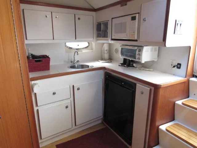 Slide: The Image of 1995 Tiara Yachts 3700 Open kitchen with white cabinets and modern appliances. - 4