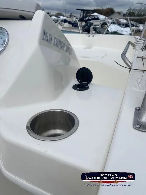 Slide: The Image of 2024 Boston Whaler 160 Super Sport boat interior with cup holder and Hampton Watercraft & Marine logo. - 18