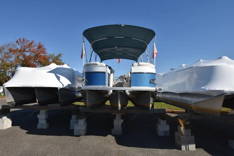 Slide: The Image of 2020 Avalon 2585 ENT SaltWater Series pontoon boat on blocks, covered for storage. - 2
