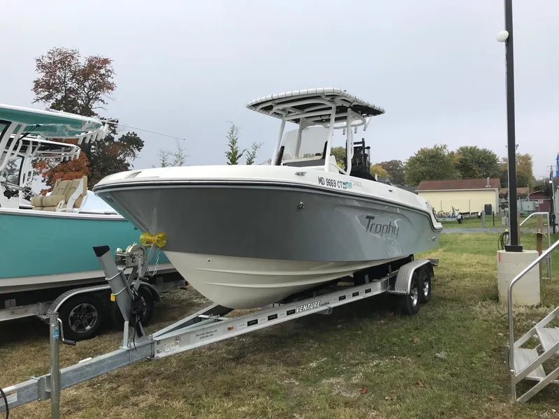Slide: The Image of 2022 Bayliner Trophy T24CC boat on a trailer in a grassy area. - 0