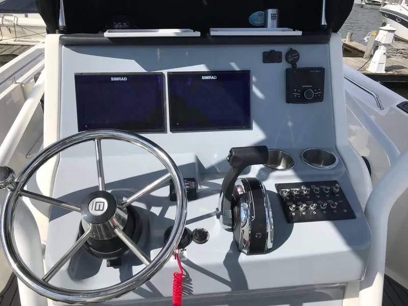 Slide: The Image of 2022 Bayliner Trophy T24CC boat dashboard with dual Simrad displays and steering wheel. - 22