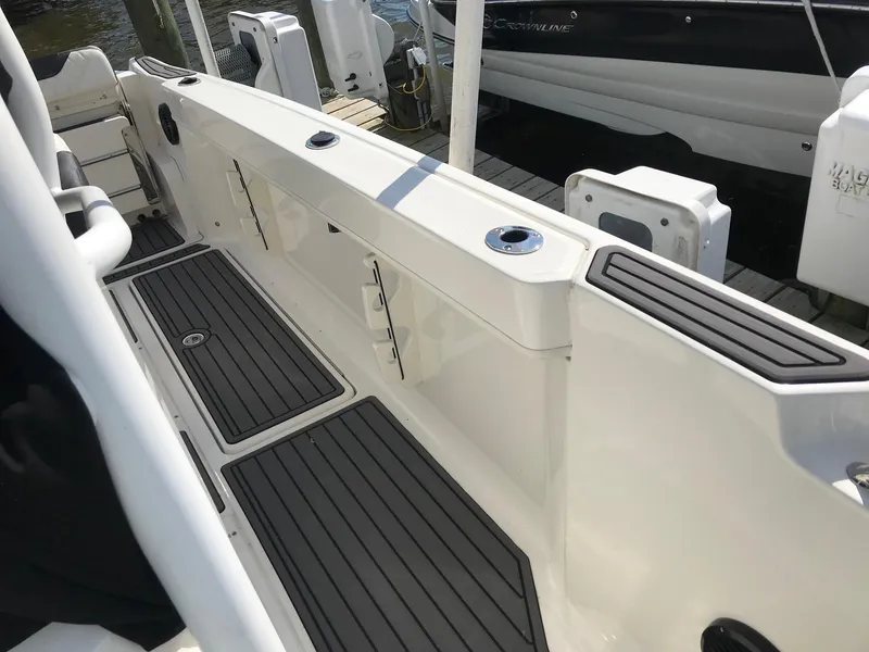 Slide: The Image of 2022 Bayliner Trophy T24CC boat interior with black deck mats and storage compartments. - 26