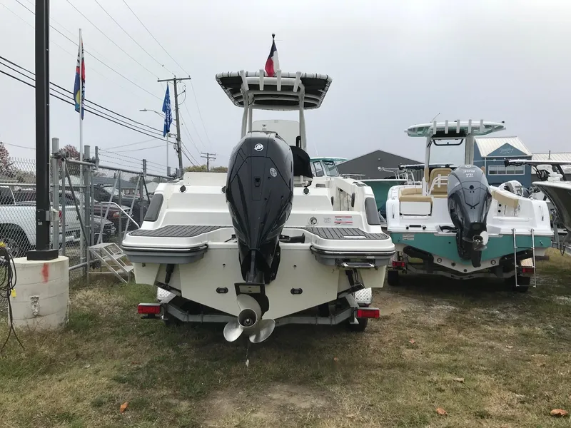 Slide: The Image of 2022 Bayliner Trophy T24CC boat with outboard motor, rear view, parked on grass. - 5