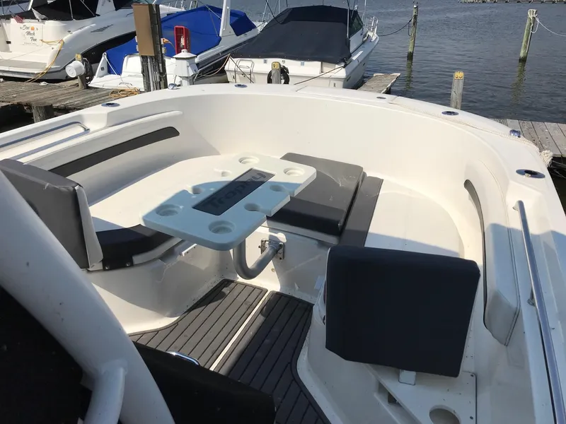 Slide: The Image of 2022 Bayliner Trophy T24CC boat interior with seating and table at a marina. - 6