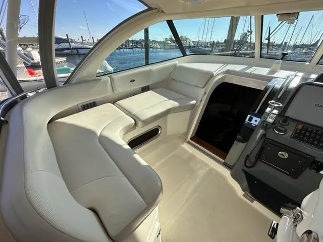 Slide: The Image of 2012 Pursuit OS 375 Offshore boat interior with white seating and navigation equipment. - 11