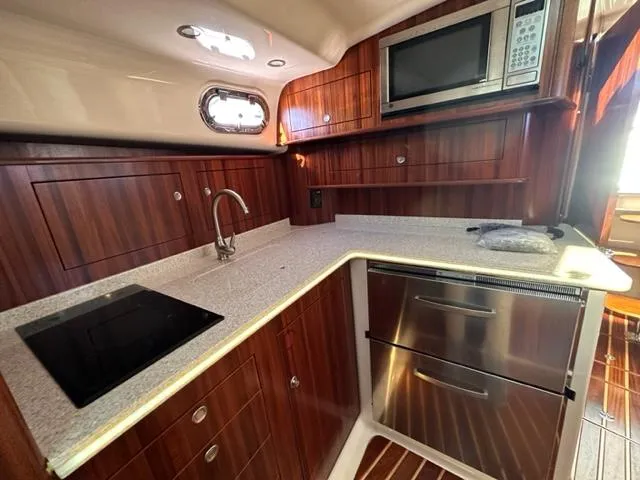 Slide: The Image of 2012 Pursuit OS 375 Offshore yacht kitchen with modern appliances and wooden cabinetry. - 22