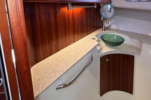 Slide: The Image of 2012 Pursuit OS 375 Offshore boat interior with wooden cabinetry and modern sink. - 33