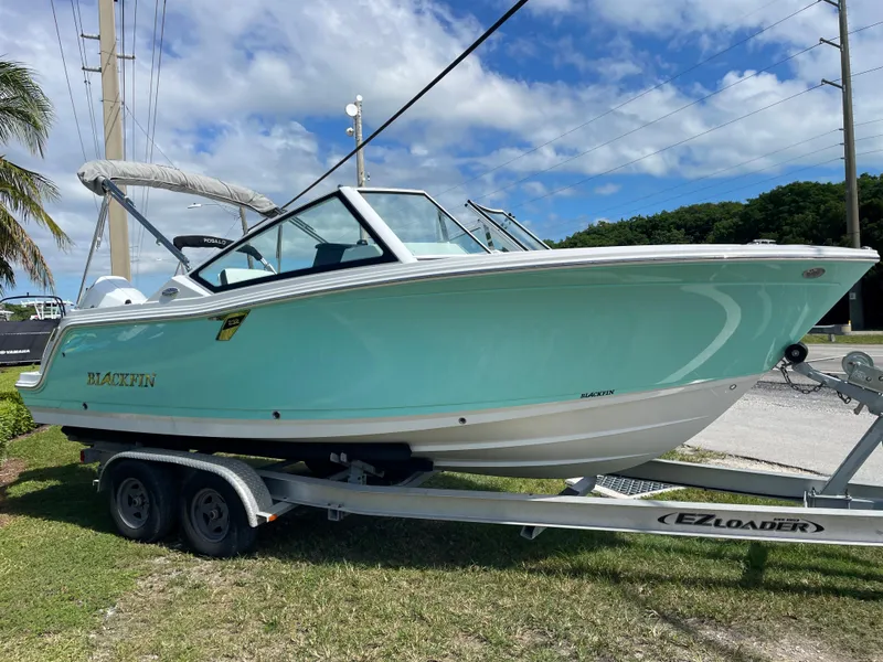 Slide: The Image of 2024 Blackfin 232DC boat on EZ Loader trailer, parked on grass. - 2