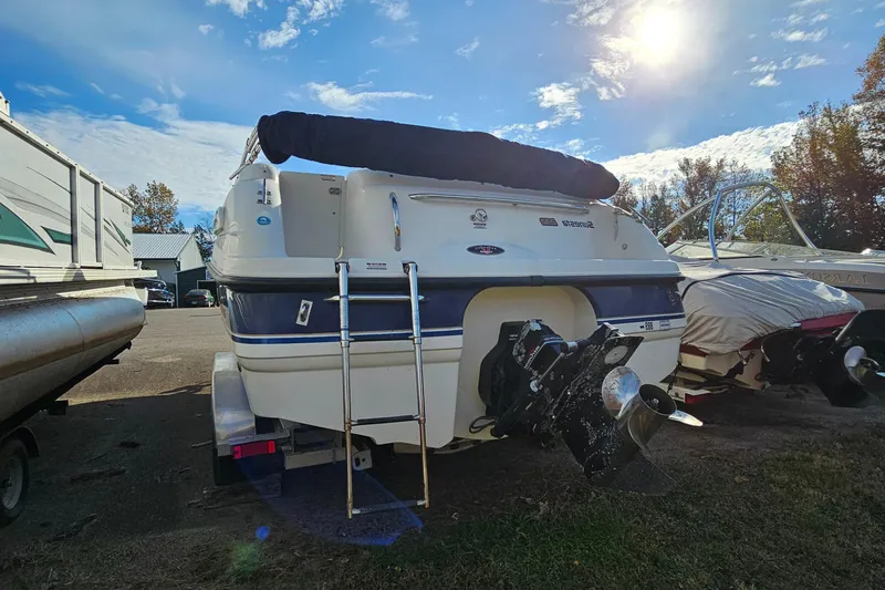 Slide: The Image of 1998 Chaparral 232 Sunesta boat with ladder, parked outdoors under a sunny sky. - 2