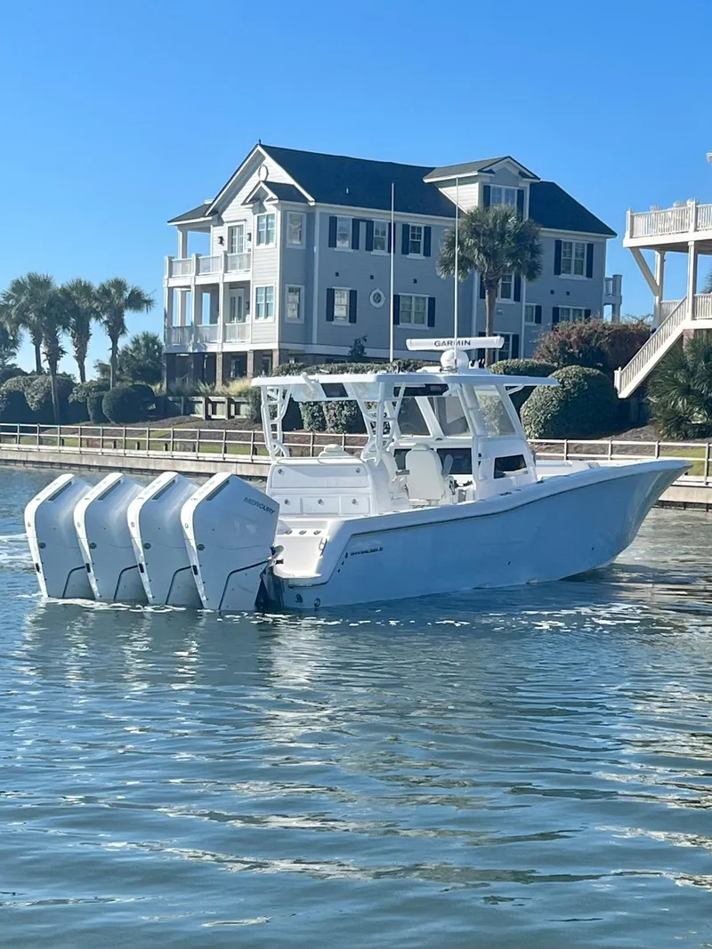 Slide: The Image of 2024 Invincible 43 Open Fisherman boat on water near waterfront homes. - 3