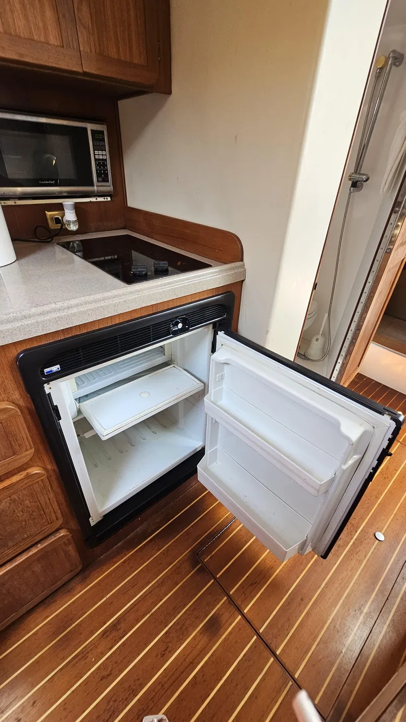 Slide: The Image of 2015 Stamas 390 Aegean interior kitchen with open fridge, microwave, and wooden flooring. - 34
