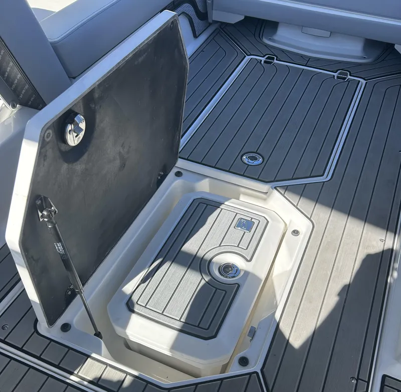 Slide: The Image of 2023 Nautique G25 boat storage compartment with open hatch. - 11