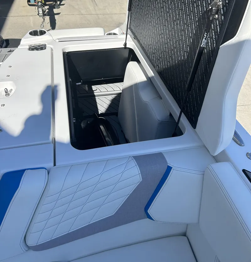 Slide: The Image of 2023 Nautique G25 boat with open storage compartment and white cushioned seating. - 12