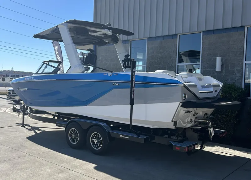 Slide: The Image of 2023 Nautique G25 boat on a trailer outside a building. - 2
