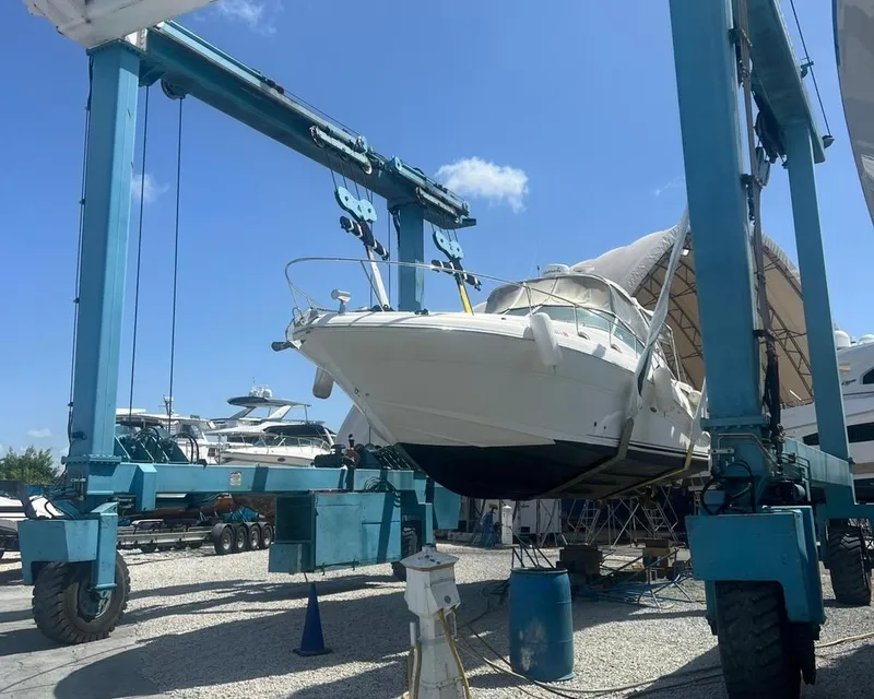 Slide: The Image of 2006 Sea Ray 340 Sundancer yacht on lift at marina under clear blue sky. - 4