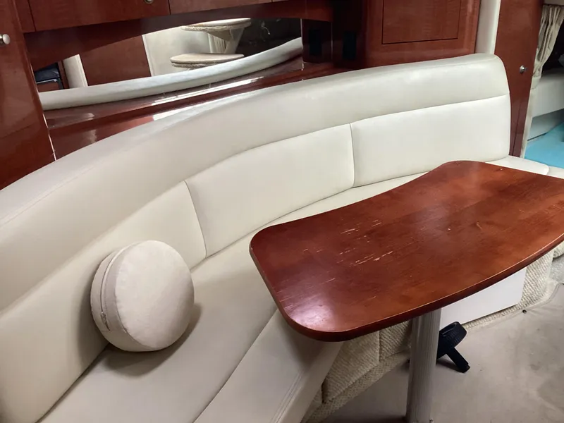 Slide: The Image of 2005 Sea Ray 320 Sundancer interior with curved seating and wooden table. - 16