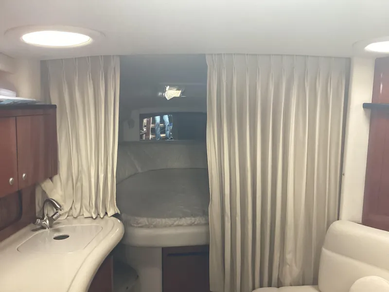 Slide: The Image of Interior of 2005 Sea Ray 320 Sundancer with bed, curtains, and kitchenette. - 19