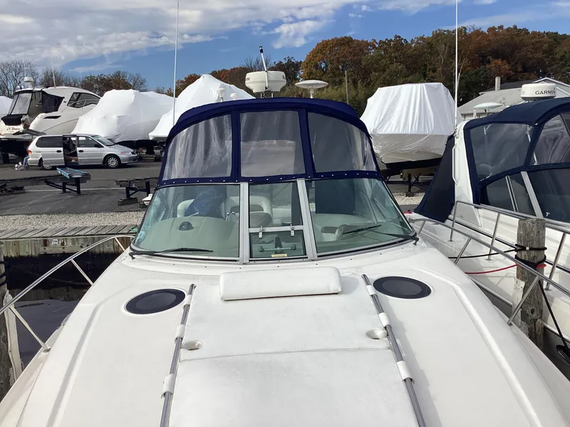 Slide: The Image of 2005 Sea Ray 320 Sundancer docked with blue canopy, surrounded by other boats. - 3